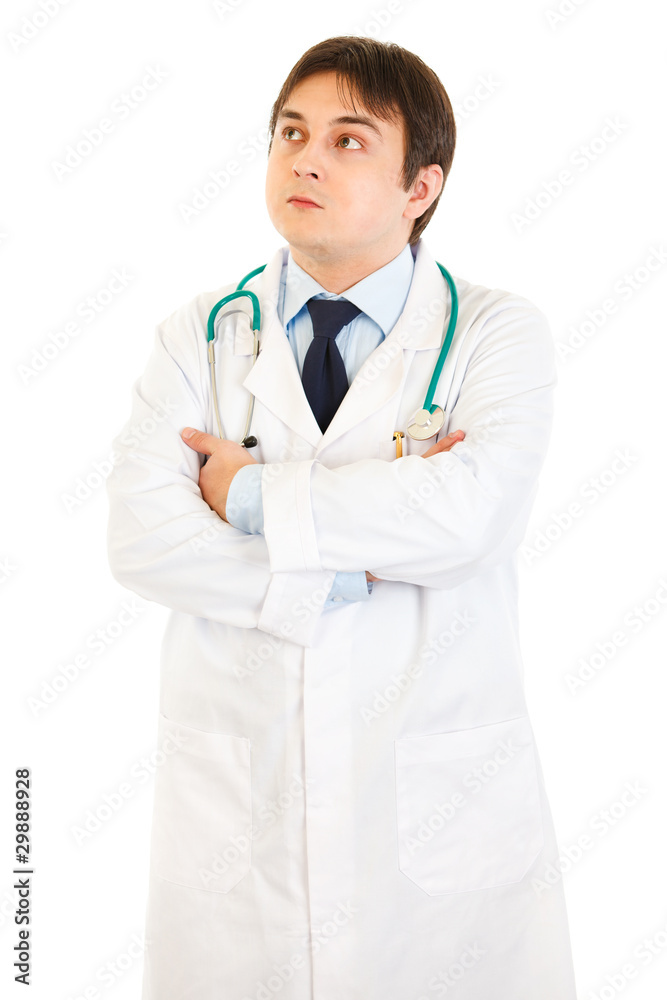 Doctor with crossed arms on chest looking up at copy space Doctor with crossed arms on chest looking up at copy space