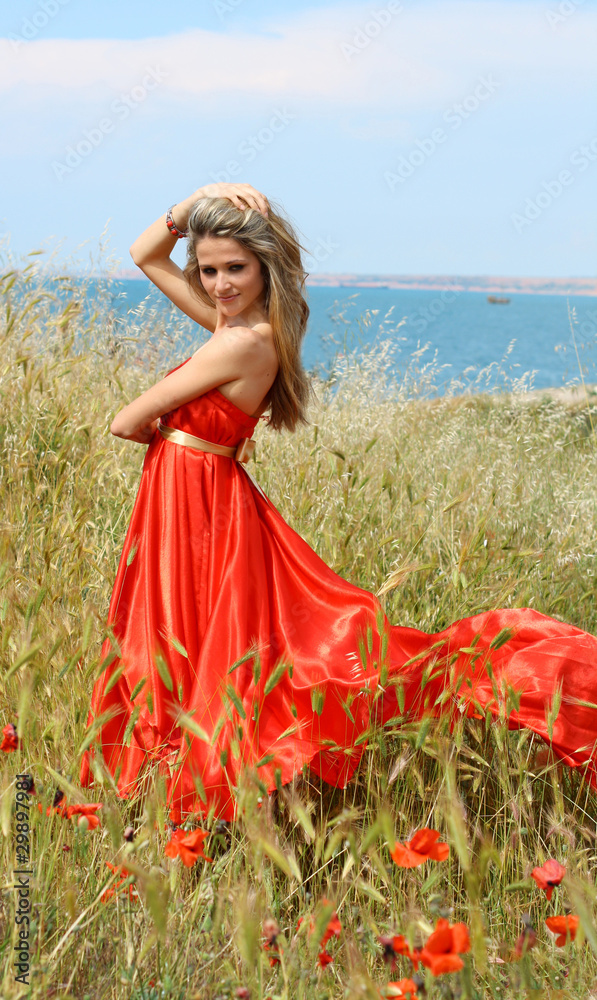 Obraz premium Outdoor shot of beautiful woman in red dress near the sea