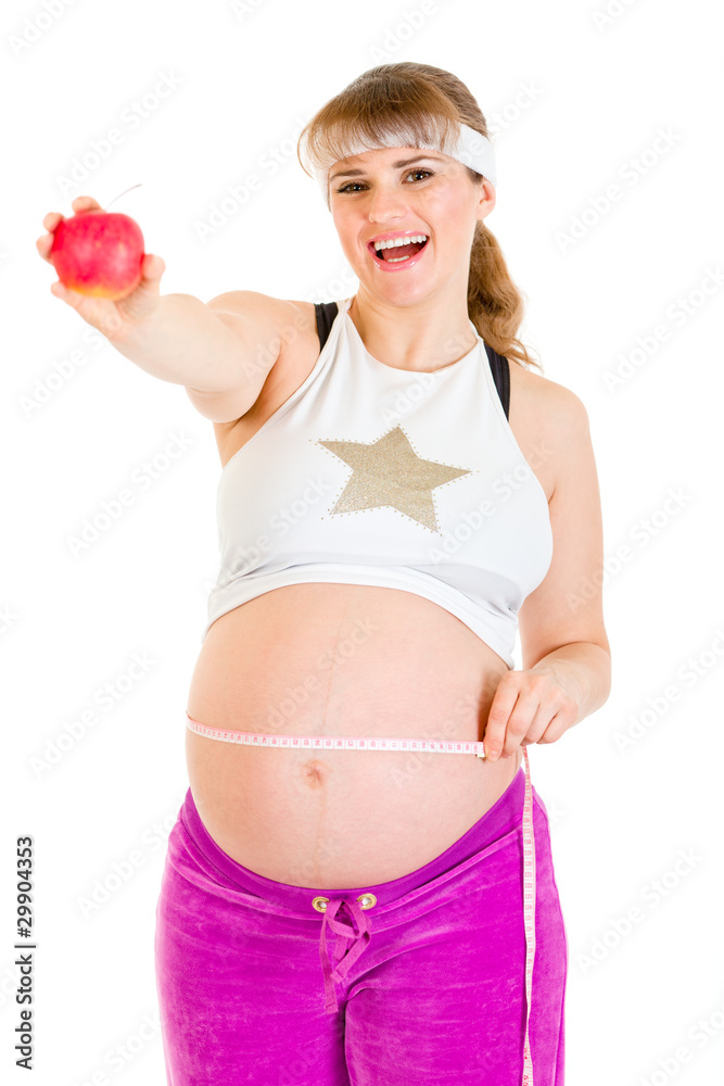 Smiling pregnant woman measuring her belly and holding apple Smiling pregnant woman measuring her belly and holding apple