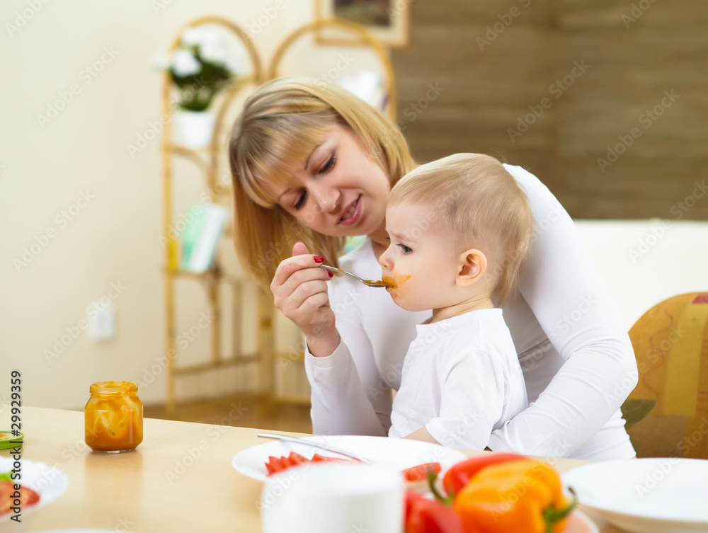 mother feeding her little son at home