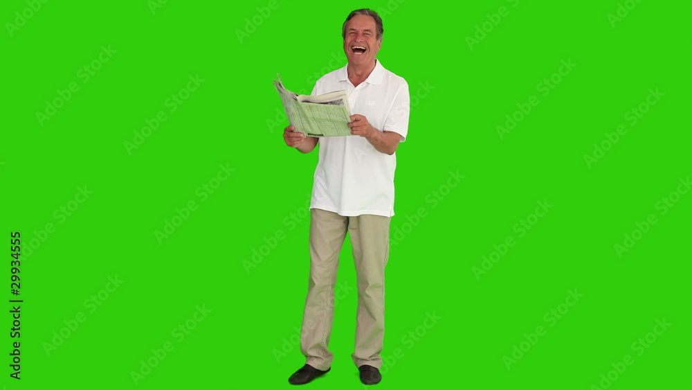 Mature man laughing while he is reading a newspaper Mature man laughing while he is reading a newspaper