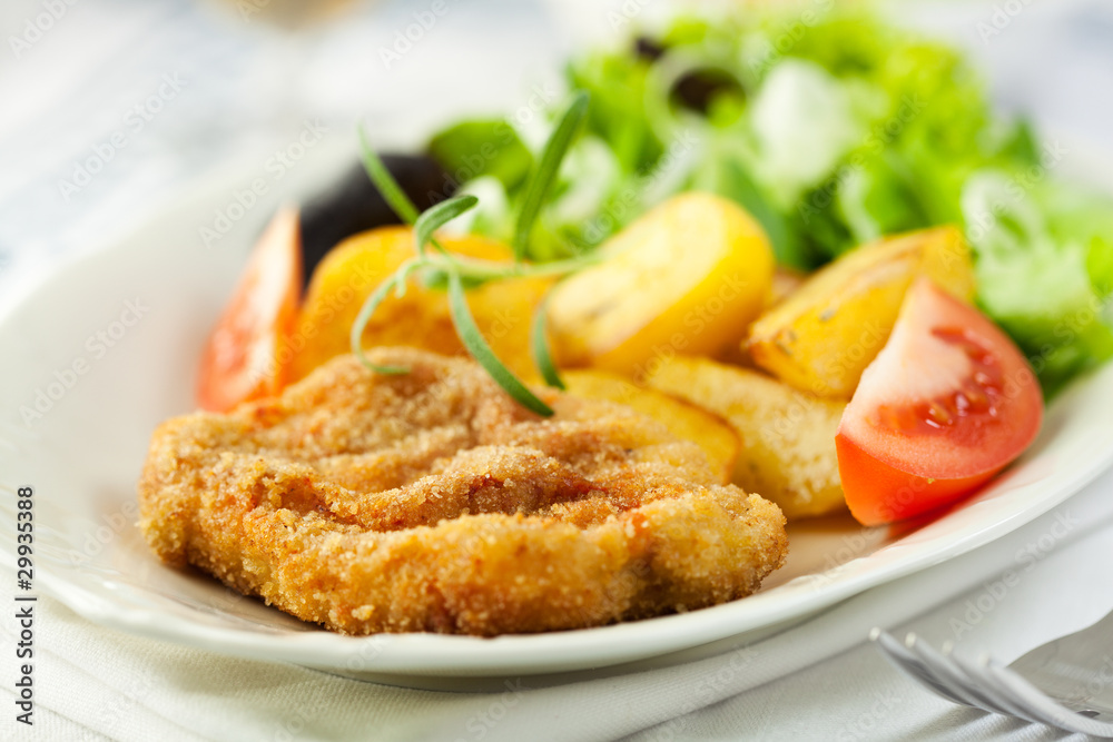 Delicious schnitzel with baked potatoes and salad
