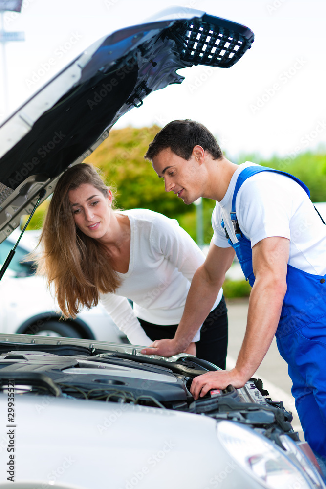 Frau spricht mit Automechaniker in Werkstatt Frau spricht mit Automechaniker in Werkstatt
