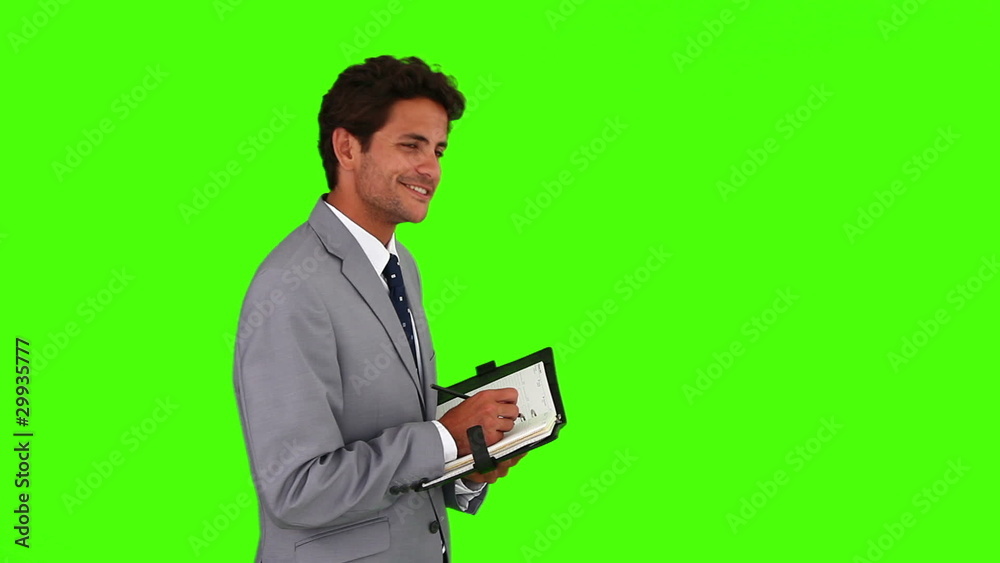 Young buisnessman in a gray suit writing something on his diary Young buisnessman in a gray suit writing something on his diary