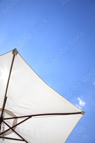 white linen umbrella in front of a deep blue sky