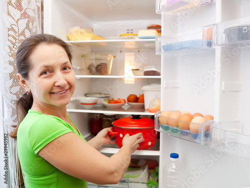 woman putting pan into fridge