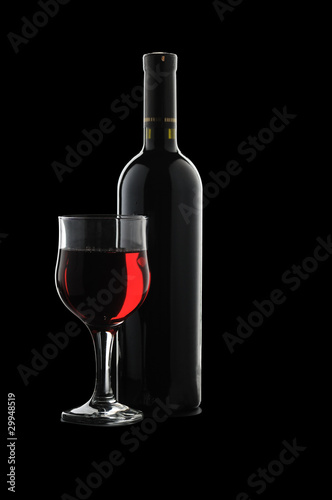 A glass of red wine and a bottle on a black background