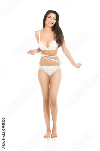 a beautiful, young woman measuring her waist line, looking unhap