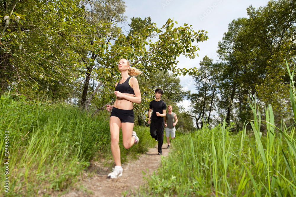 Three people running on pathway