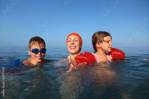 Mother in summer teaches to swim two children boy and girl