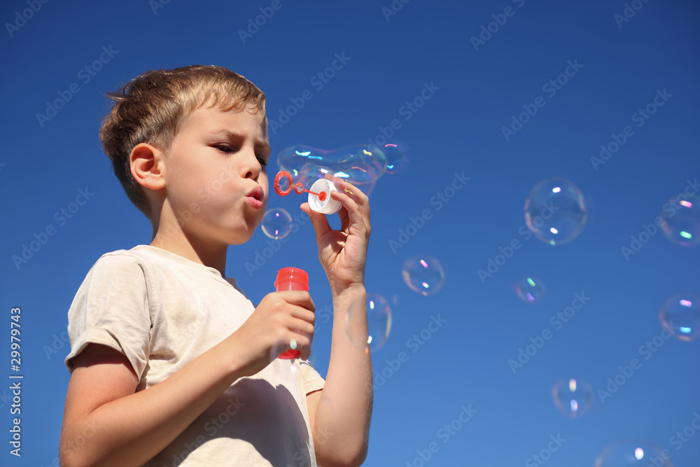 Boy stand one and inflates large soap bubbles Boy stand one and inflates large soap bubbles