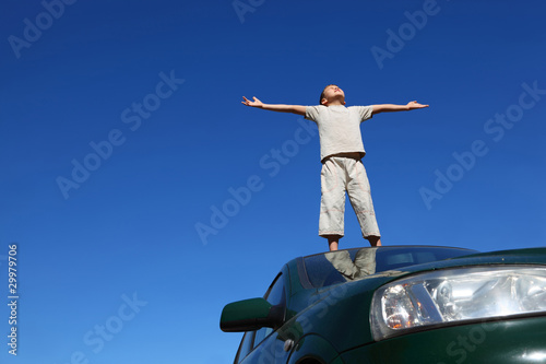Boy stands on head of car widely placing hands and heaved up