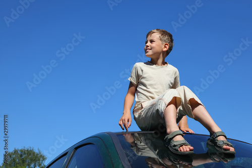 Boy sits on roof of car and looks aside © Pavel Losevsky