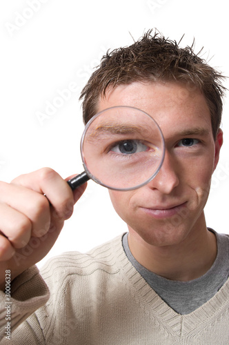 young smiling man looking through magnifying glass