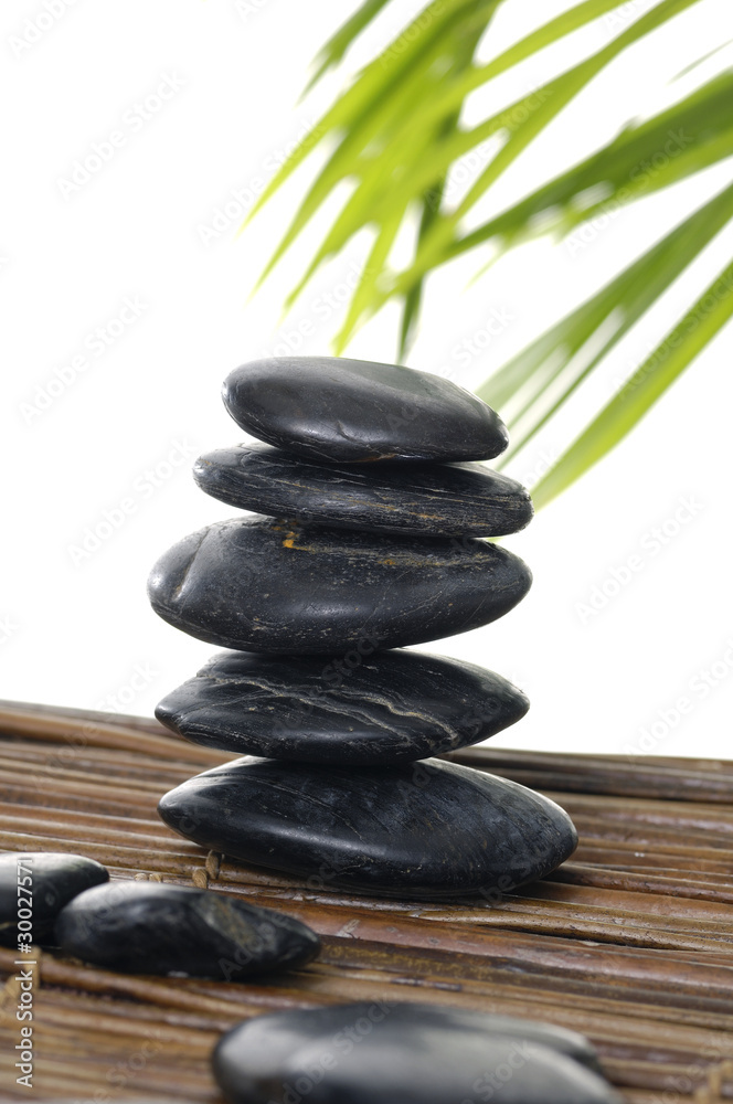 Stacked stones with palm leaf on mat Stacked stones with palm leaf on mat
