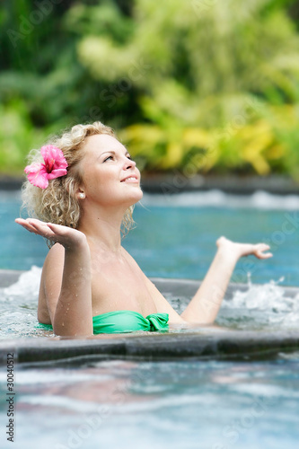 young beautiful woman relaxing in pool under rain