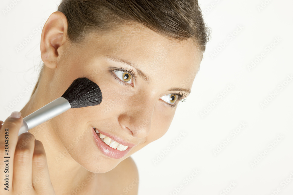 portrait of young woman putting on face powder portrait of young woman putting on face powder