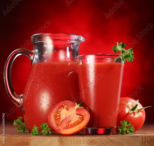 Jug and glass full of tomato juice. © volff