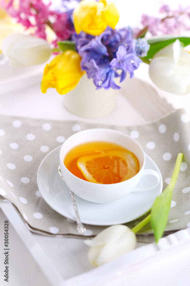 cup of tea with lemon on white tray with spring flowers cup of tea with lemon on white tray with spring flowers