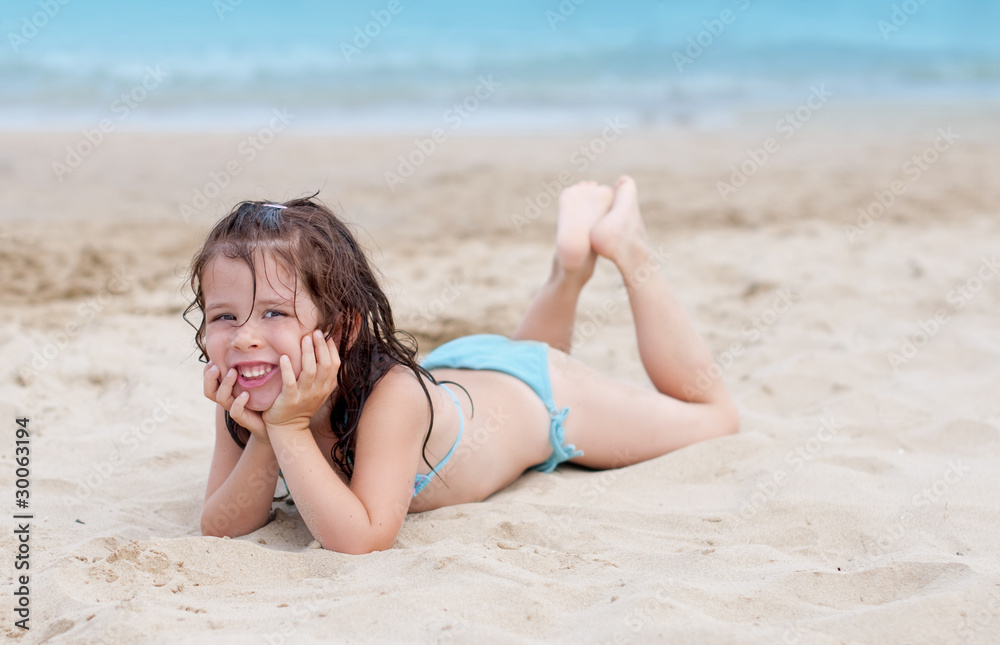Adorable little girl lying on the beach