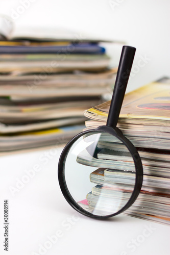 Magnifying lens  on the background of the stack of magazines