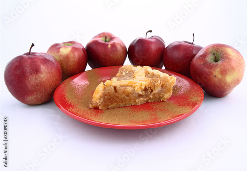 Apple Pie-slice on a plate with cinnamon and some red apples