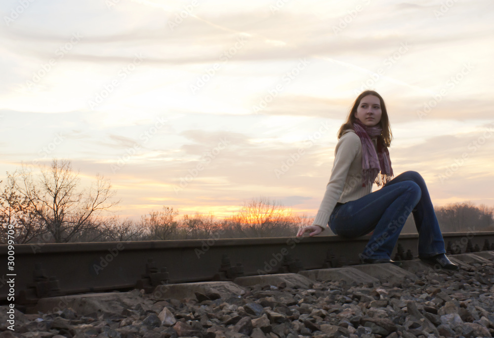 Teen girl sitting near the railways