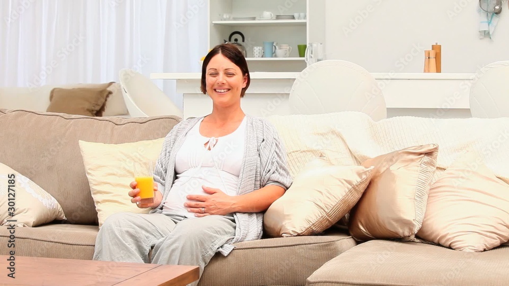 Pregnant woman drinking a glass of orange juice Pregnant woman drinking a glass of orange juice