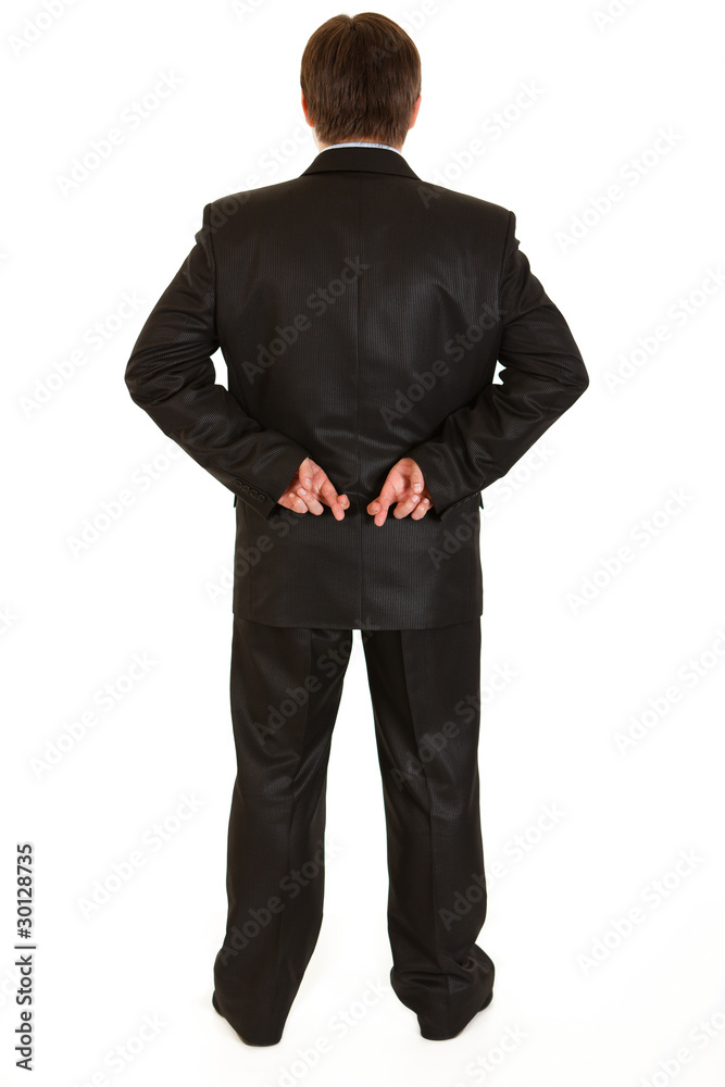 Businessman holding crossed fingers behind back Businessman holding crossed fingers behind back