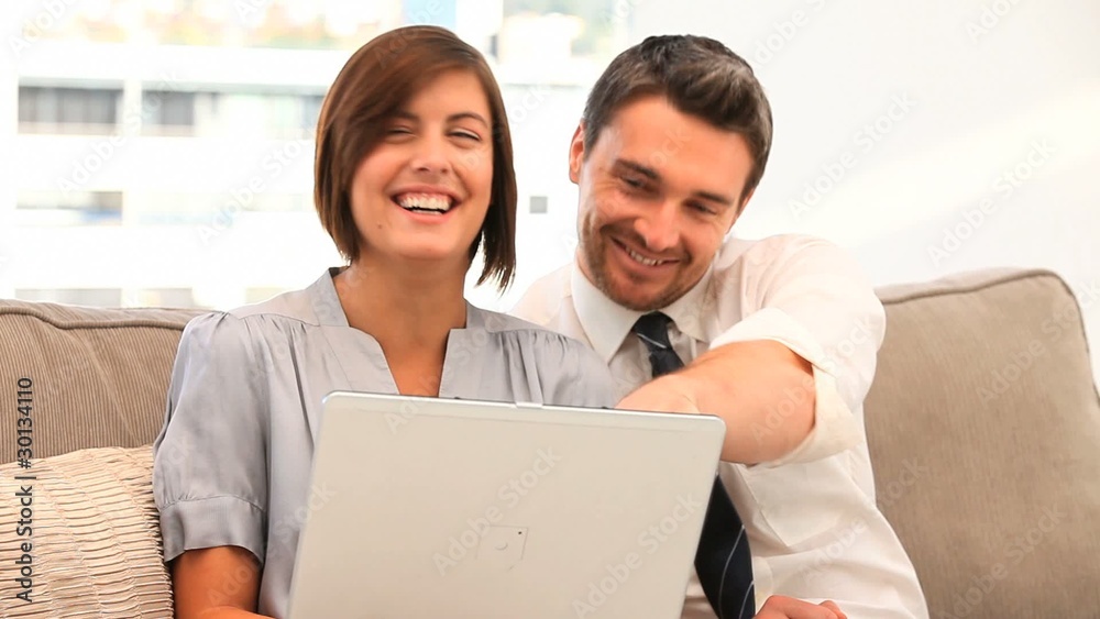 Young couple using a laptop on the sofa Young couple using a laptop on the sofa
