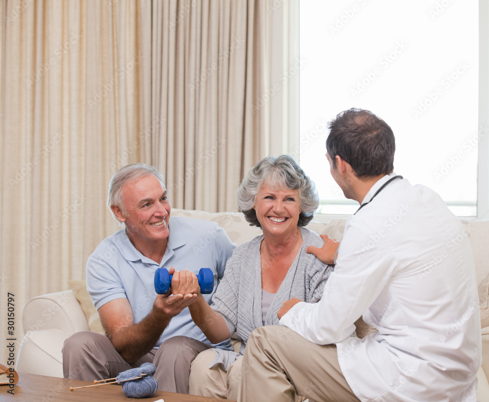 Obraz premium Handsome doctor helping his patient to do exercises