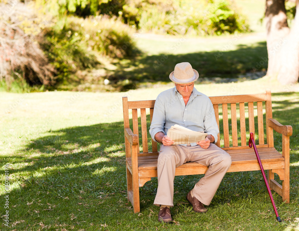 Retired man reading his newspaper on the bench