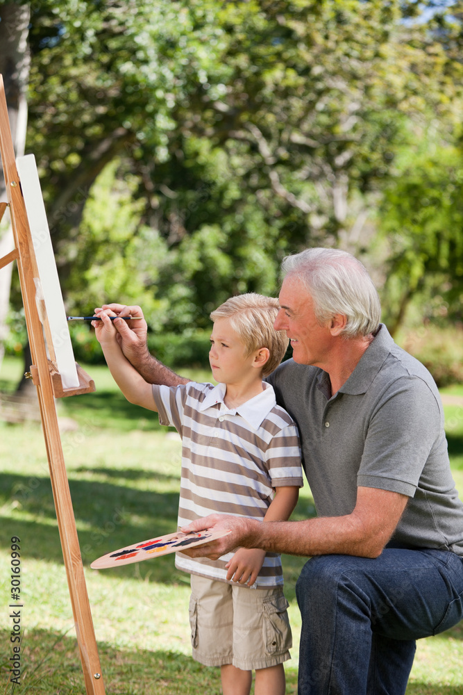 Obraz premium Happy Grandfather and his grandson painting in the garden