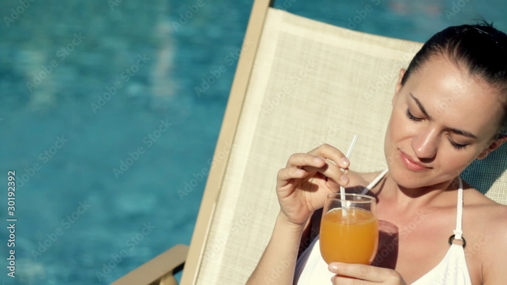 Woman lying by the pool and drinking exotic drink Woman lying by the pool and drinking exotic drink