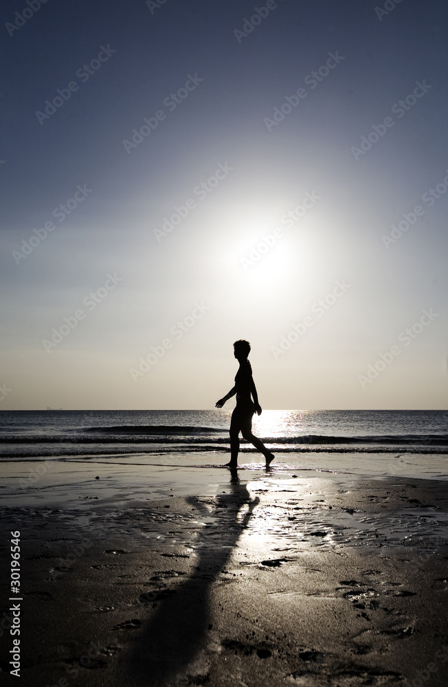 Woman strolling on the beach at sunset