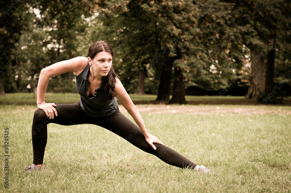 Woman performs stretching before sport in park Woman performs stretching before sport in park