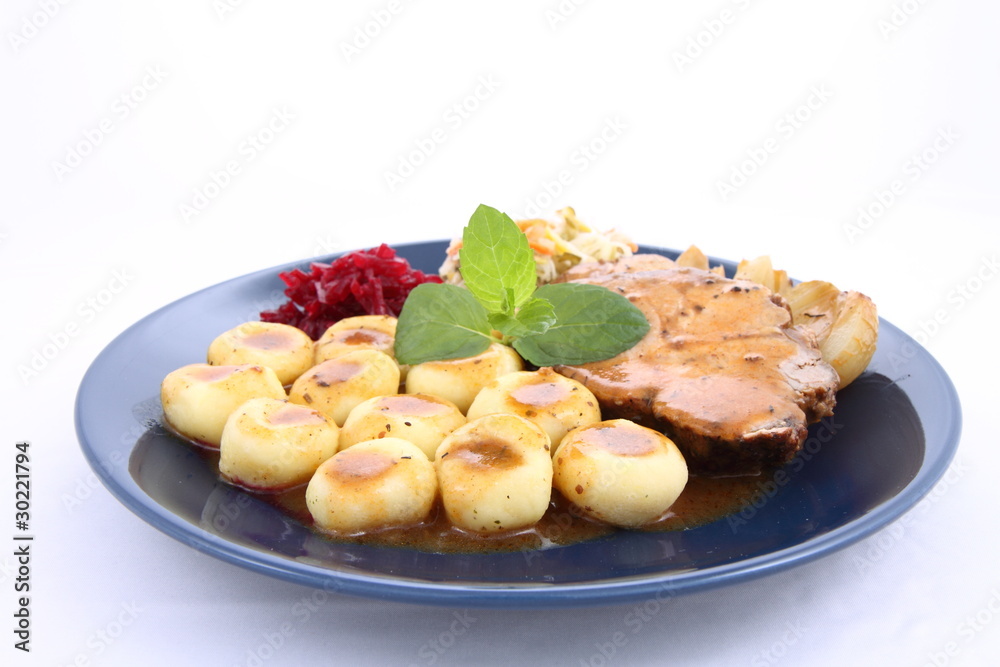 Pork steak and dumplings with side salads and a mint twig Pork steak and dumplings with side salads and a mint twig