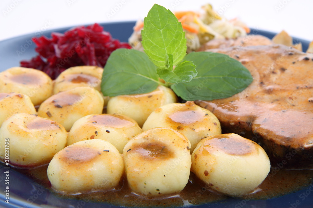 Pork steak and dumplings with side salads and a mint twig Pork steak and dumplings with side salads and a mint twig
