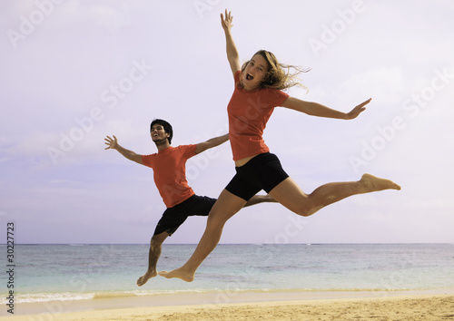 young couple jumping in the air at a hawaii beach