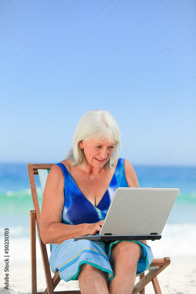 Woman working on her laptop on the beach