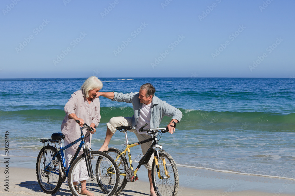 Fototapeta premium Mature couple with their bikes on the beach