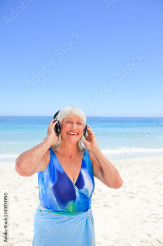 Senior woman listening to some music beside the sea