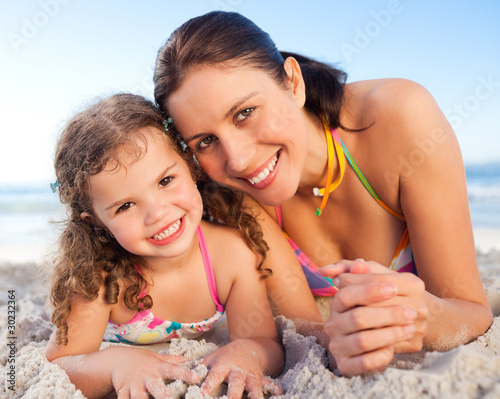 Mother and daughter lying down on the beach