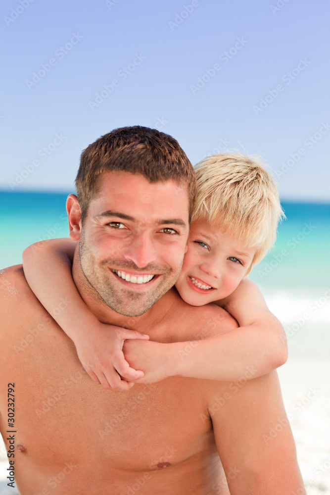 Smiling father having son a piggyback at the beach Smiling father having son a piggyback at the beach