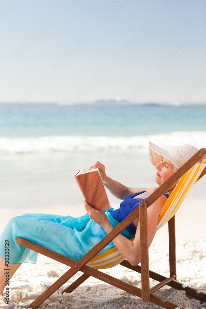 Elderly woman reading a book at the beach Elderly woman reading a book at the beach