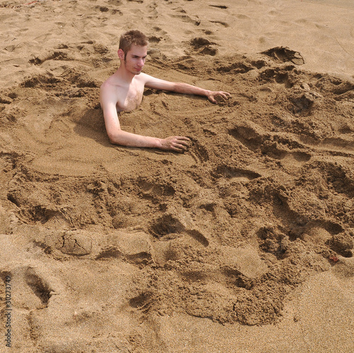 Young man burried in the sand photo