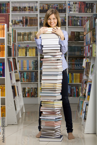 Young woman standing with big stack of books