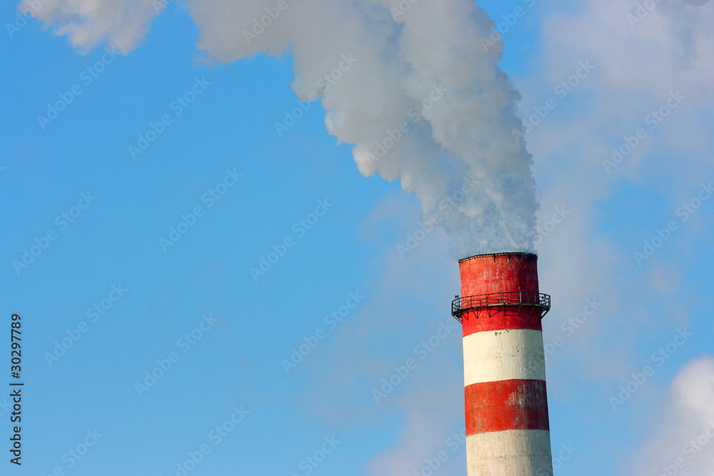 Smoking stack of the thermal power station against a blue sky Smoking stack of the thermal power station against a blue sky