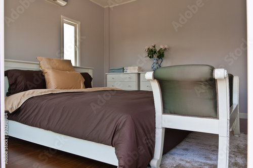 White bedroom with brown sheet bed and couch