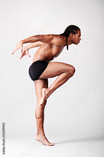 young male dancer posing over grey background